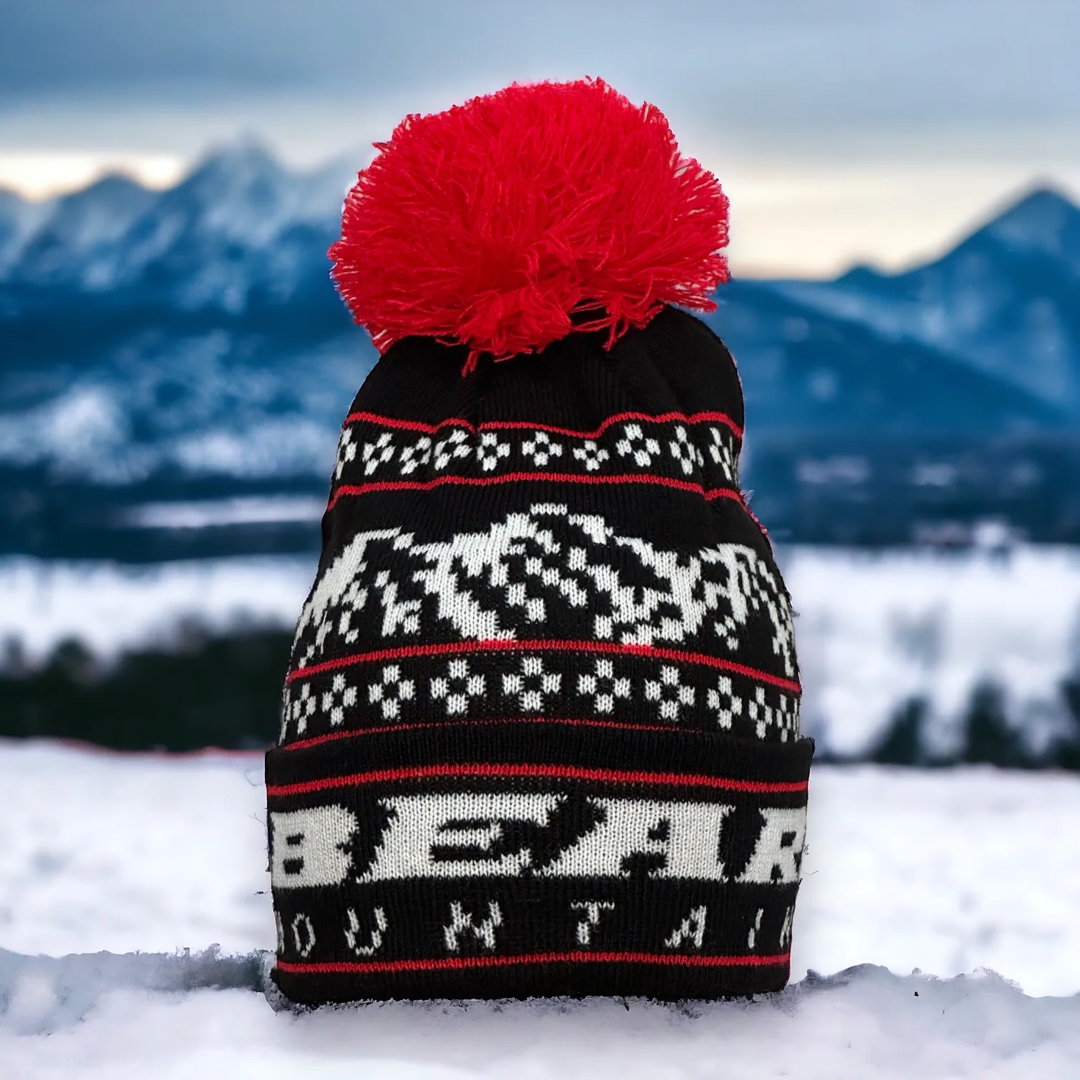 Black Beanie with white bear mountain stitching for the logo and red accent stitching with red pom pom at top.